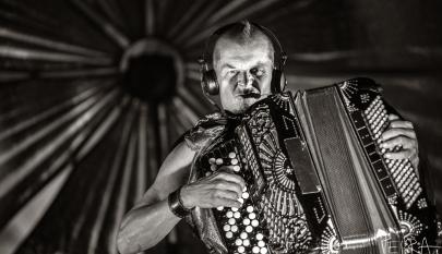 Musta-valkoisessa kuvassa mies soittaa elektro-akustista harmonikkaa