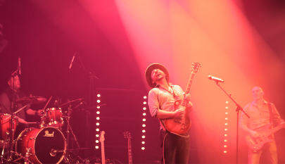 punasävyinen kuva, jossa artisti iloisesti soittaa kitaraa, muita bändin jäseniä taustalla