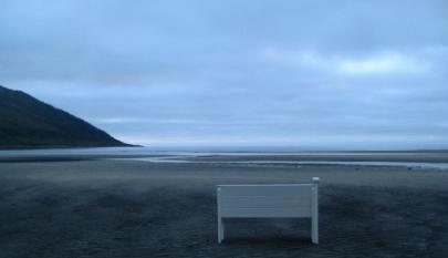 Kuvassa on penkki rannalla.