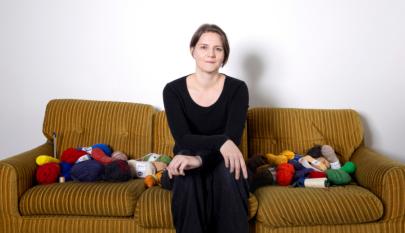 Liisa Hietanen istuu sohvalla lankakerien seassa