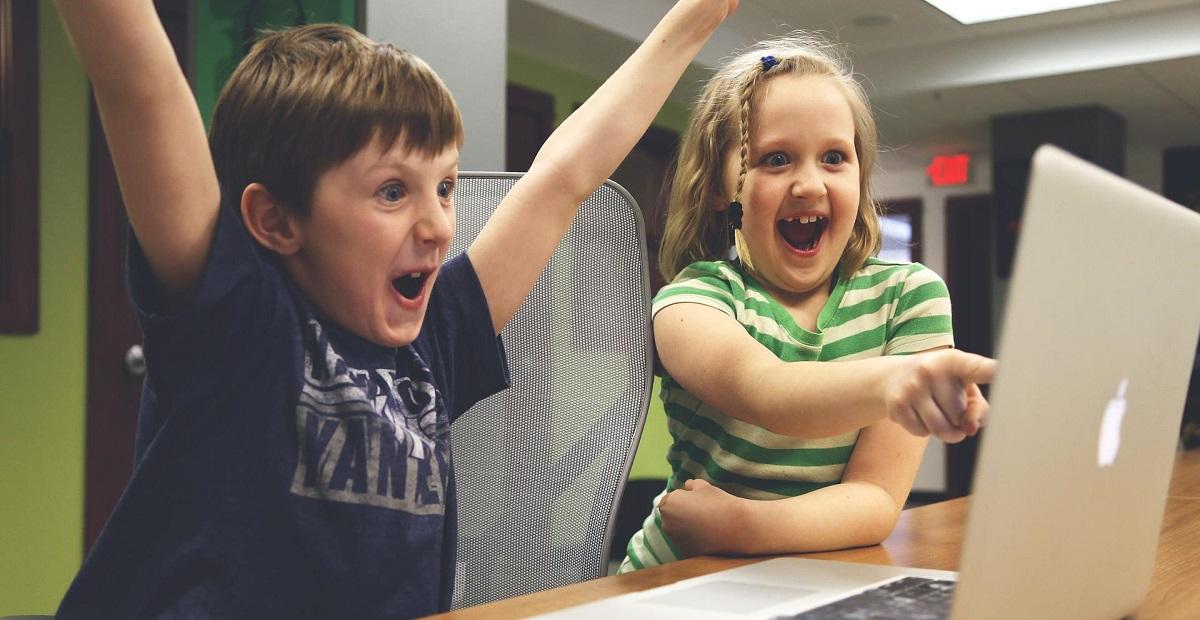 Kaksi iloista lasta pelaa Applen MacBookilla.