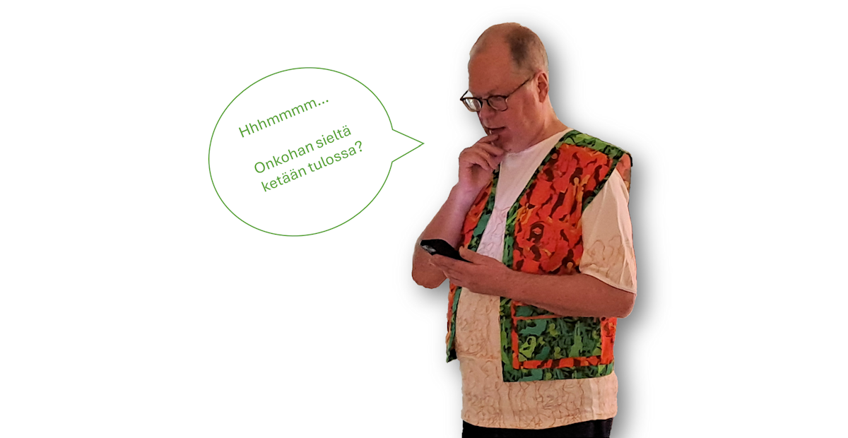 Kuvataiteilija Petri Kaverma pukeutuneena maastokuvioiseen liiviin ja puhelin kädessä. 