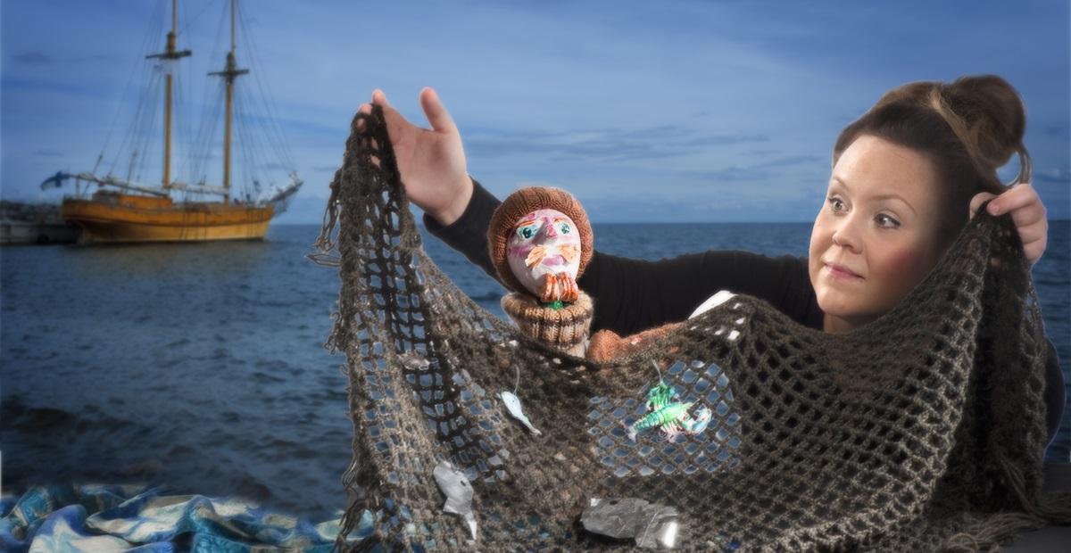 Yksi henkilö ja nukke pitelemässä kalaverkkoa.